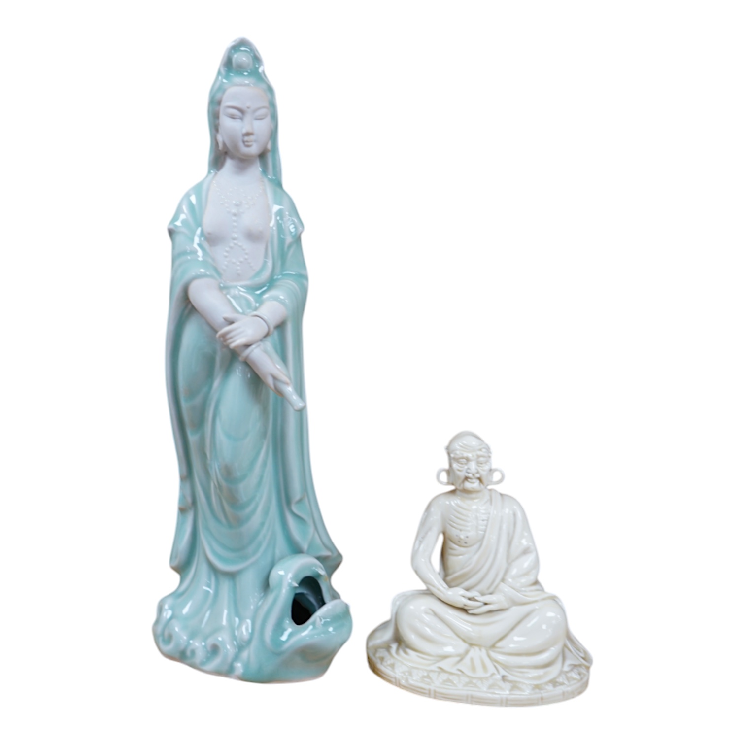 A Chinese blanc de chine seated figure of a luohan and a celadon glazed figure of Guanyin, largest 34cm high. Condition - good